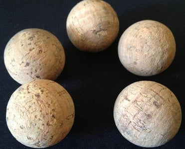 Five large natural cork balls on a black background.