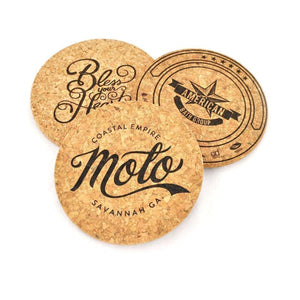 Three coasters in a triangluar layout. The top left coaster says, "Bless Your Heart" in a flowing cursive. The top right coaster says "American Bath Group" with a star in the center. The bottom coasters say, Moto Coastal Empire Savannah GA. 