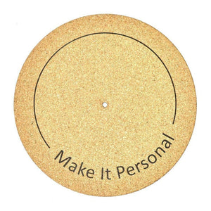 A natural cork turntable mat with a black circular line with "make it personal" written on the mat.